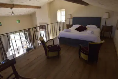 a bedroom with a bed and a balcony with chairs at Clos De La Fontaine in Cabrières-dʼAvignon
