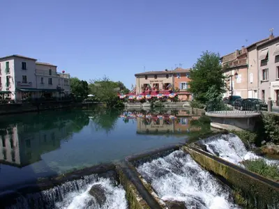 a river with a waterfall in a city with buildings at Villa in Lubéron with Saltwater Pool in Apt