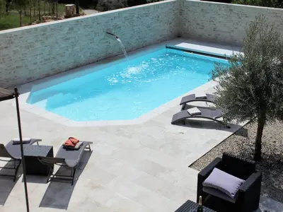 a swimming pool with a patio and chairs in a yard at Villa in Lubéron with Saltwater Pool in Apt