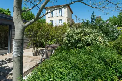 a building behind some bushes and a tree at Les Carmes and spa in Le Thor