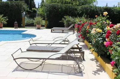 a row of lounge chairs next to a pool with flowers at Gîtes maisons de vacances Domaine la Chamade Carpentras in Carpentras
