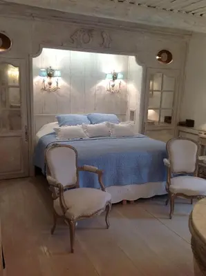 a bedroom with a large bed with two chairs at Le Clos de Lucie in Lagnes