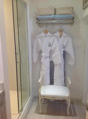 a dressing room with white shirts and a chair at Le Clos de Lucie in Lagnes