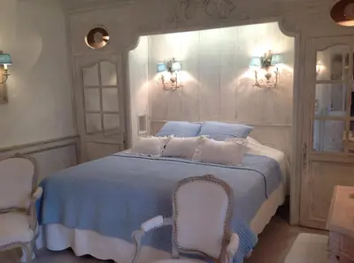 a bedroom with a blue bed with two chairs at Le Clos de Lucie in Lagnes