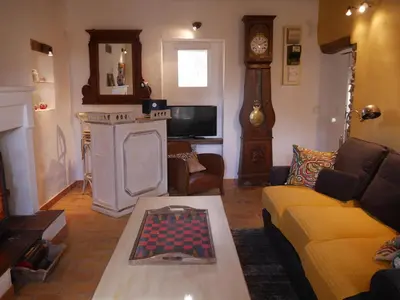 a living room with a yellow couch and a clock at L'Escarpolette in Saint-Saturnin-les-Apt