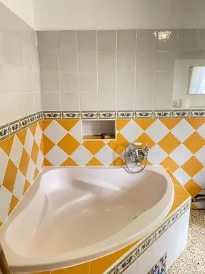 a bath tub in a bathroom with yellow and white tiles at L'Escarpolette in Saint-Saturnin-les-Apt