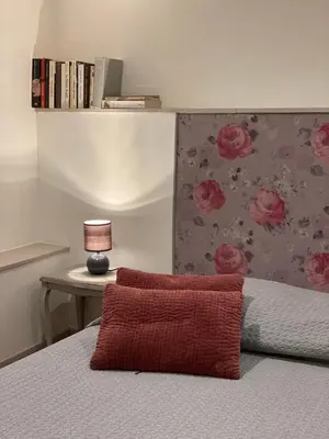 a bed with a red pillow and a table with a lamp at L'Escarpolette in Saint-Saturnin-les-Apt