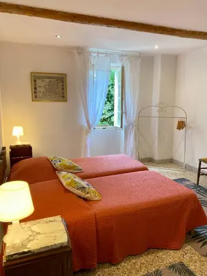 a bedroom with a bed with an orange blanket and a window at L'Escarpolette in Saint-Saturnin-les-Apt