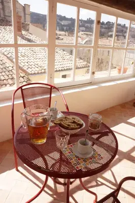 a table with a plate of food and drinks on a balcony at Longo Mai in Apt
