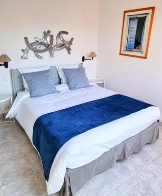 a large bed in a bedroom with a blue blanket at Hôtel Le Mas des Grès & Restaurant Sous les Platanes in Lagnes