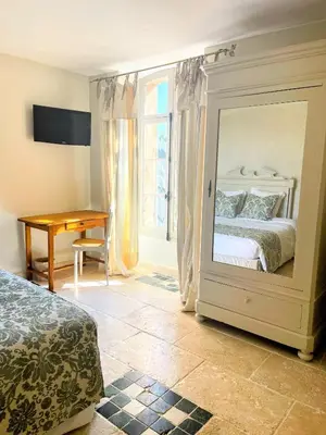 a bedroom with a bed and a desk and a mirror at Hôtel Le Mas des Grès & Restaurant Sous les Platanes in Lagnes