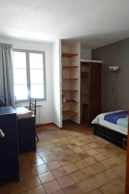 a bedroom with a bed and a desk and a window at L'Enclos in Aix-en-Provence