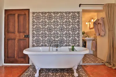 a white bath tub in a bathroom with a wallpaper at Le Jardin de Mazan in Mazan