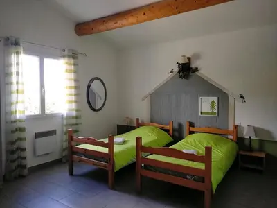 a bedroom with a bed with green sheets and two chairs at La Sarriette - Chambres d'hôtes et gîte d'étape à Eygalières in Eygalières