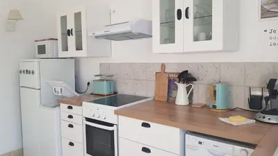 a kitchen with white cabinets and a wooden counter top at Mas Nina Rosa in Mazan