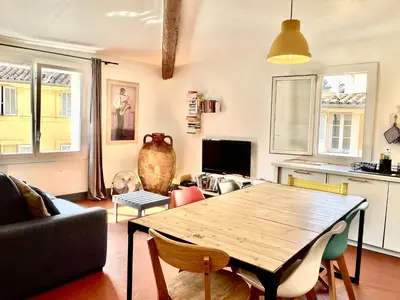 a living room with a wooden table and a couch at Lumineux Aix Plein Centre avec Parking privé Gratuit in Aix-en-Provence