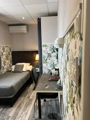 a small bedroom with a bed and a table at Hôtel de Charme Le Provence in Salon-de-Provence
