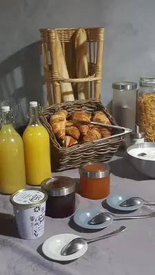 a table with a basket of bread and bottles of orange juice at Hotel Belvue in Sault-de-Vaucluse