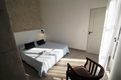 a small bedroom with a bed and a chair at Les Guillaume Rey in Oppède