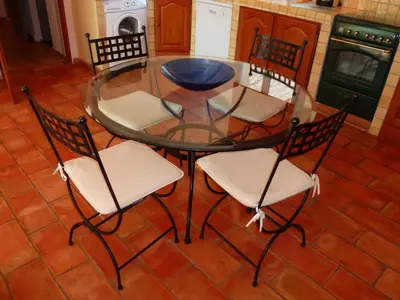 a glass table and four chairs in a kitchen at Luberon & Lavandes in Roussillon