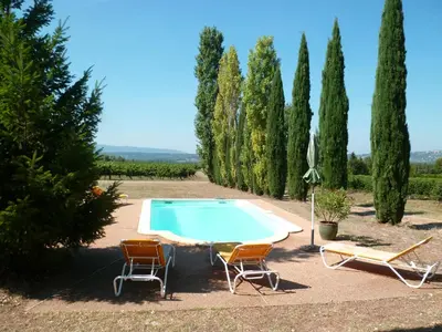 a swimming pool with two chairs and a table at Luberon & Lavandes in Roussillon