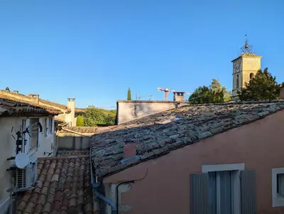 an alley between two buildings with a clock tower at L'Aiguebelle in Céreste