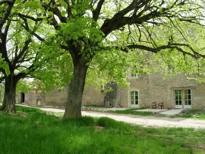a stone building with two trees in front of it at Château de la Gabelle Férrassières in Ferrassières
