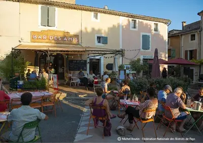 a group of people sitting at tables outside a restaurant at Bar des Amis in Villars