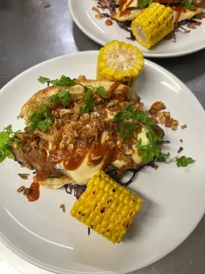 a white plate of food with corn on the cob at Bar des Amis in Villars