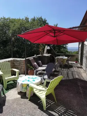 a patio with chairs and a red umbrella and a table at Mas Saint Louis in Saignon