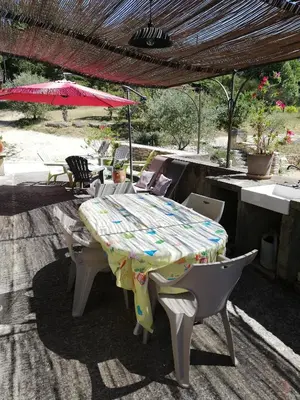 a man sitting at a table under an umbrella at Mas Saint Louis in Saignon
