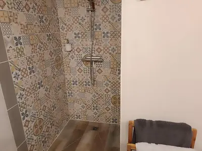 a bathroom with a shower with mosaic tiles at Mas Auroma in Murs