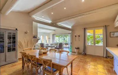 a kitchen and living room with a wooden table and chairs at Le Chant du Coeur in Roussillon