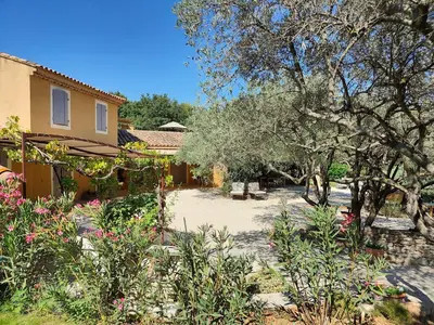 a garden with flowers and trees and a house at Le Chant du Coeur in Roussillon