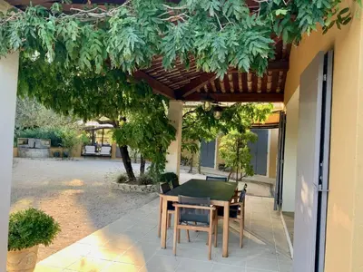 a patio with a table and chairs under a pergola at Le Chant du Coeur in Roussillon