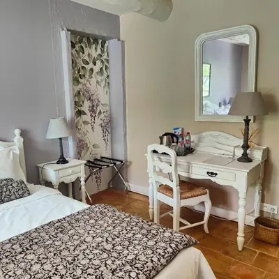 a bedroom with a desk and a bed and a mirror at Le Chant du Coeur in Roussillon