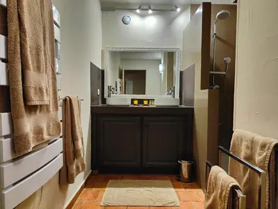 a bathroom with a black vanity and a mirror at Le Chant du Coeur in Roussillon