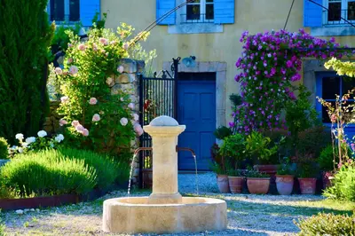 a fountain in front of a house with flowers at Bastide Saint-Didier in Saint-Didier