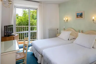 a hotel room with two beds and a window at Hôtel Le Mozart in Aix-en-Provence