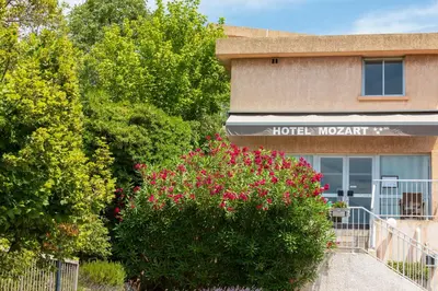 a hotel lobby with pink flowers in front of a building at Hôtel Le Mozart in Aix-en-Provence