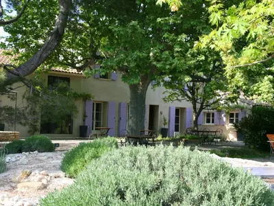 a building with tables and trees in front of it at Couleur Lavande in Le Thor
