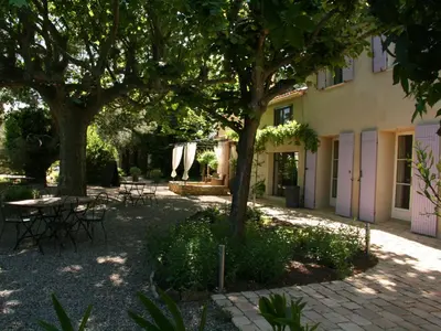 a courtyard with tables and chairs and trees at Couleur Lavande in Le Thor