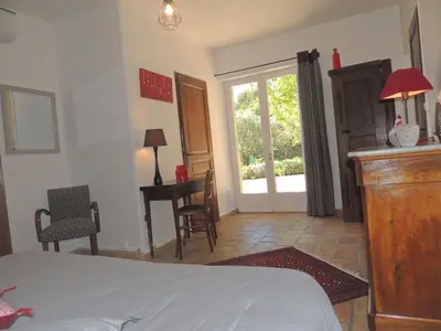 a bedroom with a bed and a window and a table at Les Chênes Verts in La Bastidonne