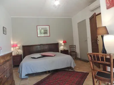 a bedroom with a bed and two chairs and a table at Les Chênes Verts in La Bastidonne