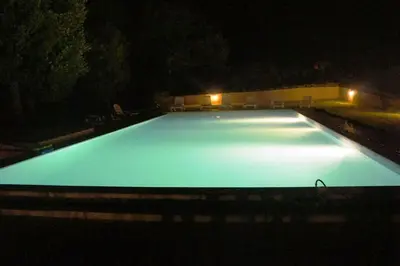 an empty swimming pool at night with lights at Les Chênes Verts in La Bastidonne