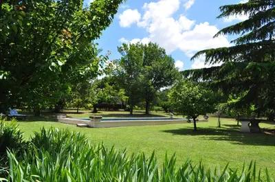a park with a fountain and trees and grass at La roulotte Chic et Boheme in Mazan