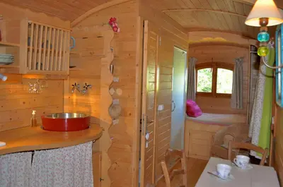 a kitchen in a log cabin with a sink and a window at La roulotte Chic et Boheme in Mazan