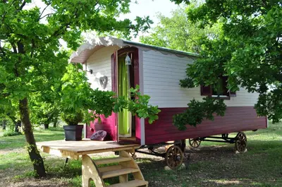 a red and white tiny house sitting in a field at La roulotte Chic et Boheme in Mazan