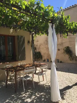 a table and chairs under a tree with an umbrella at Maison de vacances Jocelyne in Lauris