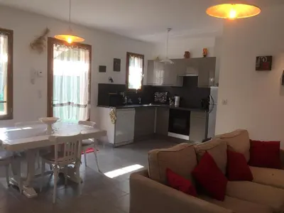 a living room with a couch and a table and a kitchen at Maison de vacances Jocelyne in Lauris